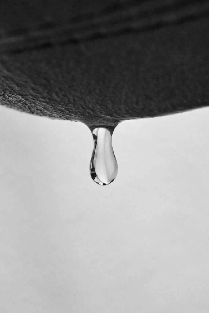 Close-up capture of a single water droplet in a monochrome setting, showing intricate details.